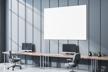 Modern empty office interior with long desk, chairs, computers, and a large blank canvas on blue wall under sunlight in corporate workspace.. 3D Rendering