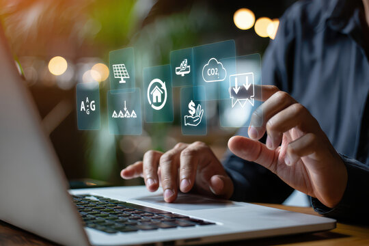 Person using laptop with floating green energy and sustainability icons above the keyboard area