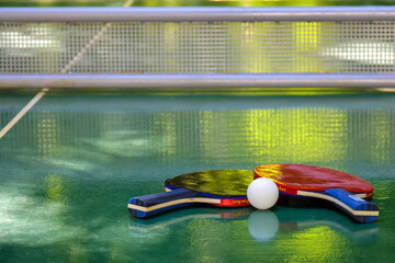 Two ping pong racket and white tennis ball on green tennis table. Close-up. Copy space. Selective...