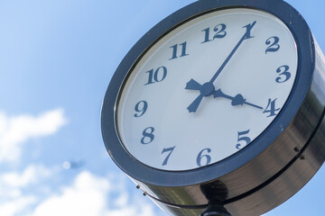 Classic Clock Under a Clear Blue Sky Near a Park, Showcasing the Time Just Before Four Oclock in...