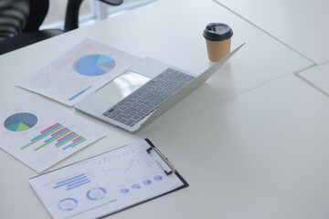 computer laptop with financial data graph analysis on the table in the meeting room.