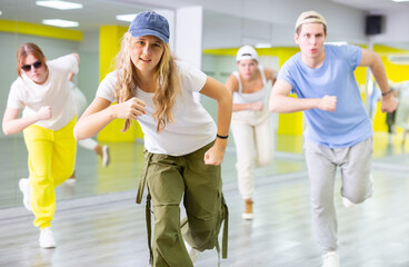 Dynamic teenage girl in cap training breakdance Toprock moves during workout session. Teens doing...