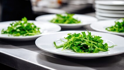 Fresh arugula salad on white plates, ready for service in a kitchen