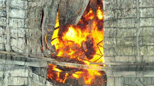 Drone footage shows a catastrophic blaze tearing through a structure&rsquo;s roof, with bright flames visible from above, highlighting the scale of the emergency response needed.
