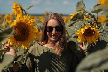 A girl in a pink skirt and a white T-shirt walks through a field of blooming yellow sunflowers. A woman dances, rejoices, smiles, enjoys life, warmth, summer, the sun. High quality FullHD footage