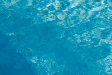 blue blurred textured swimming pool water surface waving motion by wind blow at noon sunshine