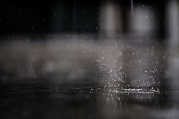 raining on the concrete walk way full with rain droplets splash ring bounce off the surface of water with reflected of white cloudy sky