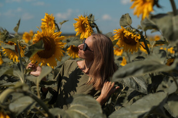 A girl in a pink skirt and a white T-shirt walks through a field of blooming yellow sunflowers. A woman dances, rejoices, smiles, enjoys life, warmth, summer, the sun. High quality FullHD footage