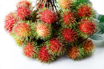 Fresh rambutan fruit on white wooden table.