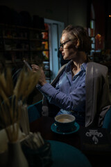 woman looking at smartphone and drinking coffee in restaurant
