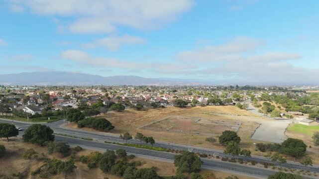 Wide aerial of Natividad Creek Park showing grass fields and walking trails on a sunny day, ascend overview