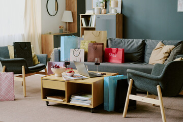 Living room scene showing shopping bags arranged on sofa and floor near wooden coffee table with...