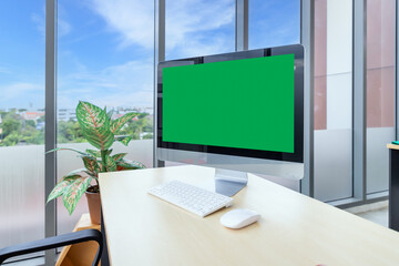 Modern office desk with computer monitor green screen and indoor plant