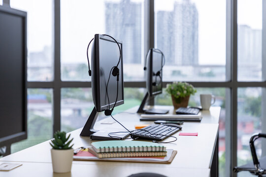 Call center desk with computer monitor, headset, keyboard, and office supplies - Powered by Adobe