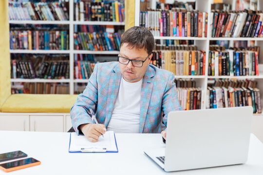 Business man in glasses working on laptop online in library