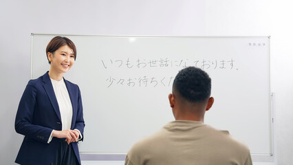 黒人男性に日本語学校でビジネス用語を教える女性教師