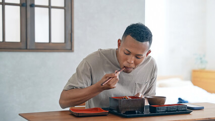 飲食店で鰻重を食べる外国人男性