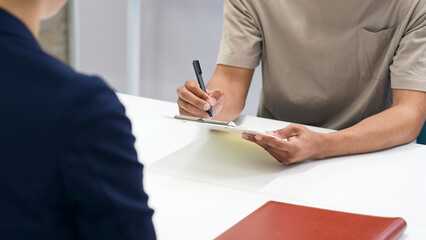 A black man and a Japanese female staff member signing documents
