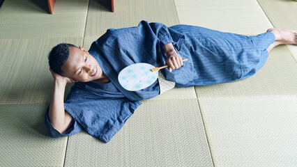 浴衣を着て畳に寝転んで涼む外国人男性