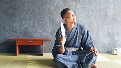 A black man wearing a yukata relaxing on a tatami mat