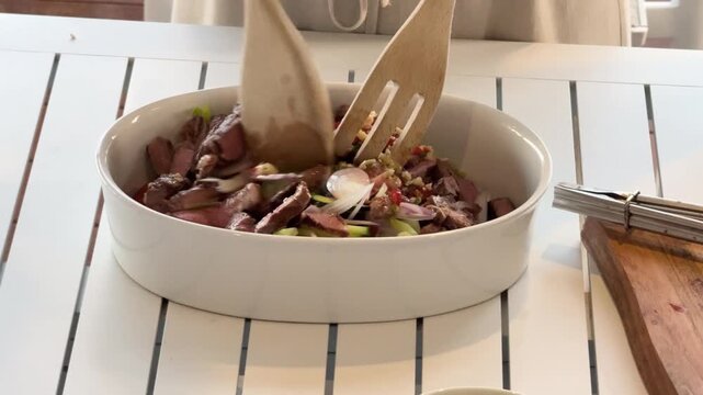 Mixing Spicy Thai Beef Salad in Sunlit Kitchen
