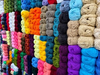 A vibrant collection of multicolored wool yarn balls arranged closely, captured with a shallow...