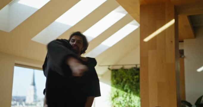 Male dancer lifts his partner effortlessly over his shoulders as they rehearse in a bright modern studio with high ceilings and natural wooden elements