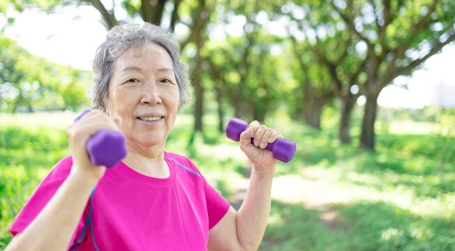 Happy Asian senior woman lifting dumbbell