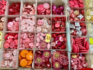 A plastic storage container packed with a massive, colorful assortment of buttons for arts and crafts.
