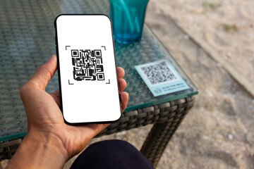 online payment with QR code on smartphone ,mobile banking application and man hand using smatphone and QR code on table background
