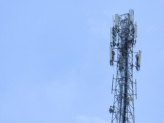 Tall mobile communication tower standing against clear blue sky with antennas and cellular transmitters for signal