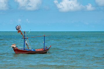 Fishing Boat Anchored in Turquoise Waters off the Coast During a Clear Sunny Day With Scattered...