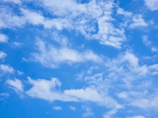 Textured sky filled with wispy white clouds spread across bright blue background