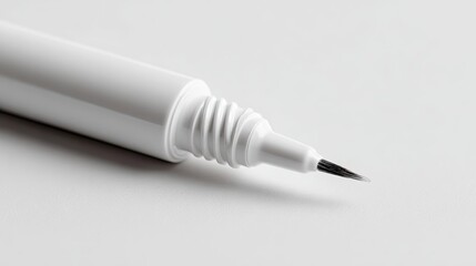 Close-up shot of a white eyeliner pen with a fine black tip, resting on a white surface.