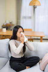 Young woman holding tissue with runny nose