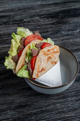 Homemade flatbread with beef and tomatoes on a table in a cafe. 