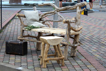 Rustic wooden bench and stool set made of driftwood on a paved street