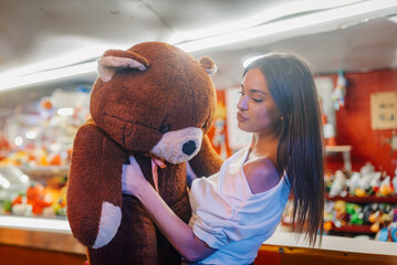 Young woman holding giant teddy bear at amusement park