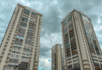 Three tall buildings with many windows and a cloudy sky in the background