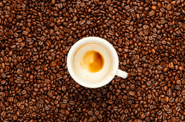 Top view of an empty espresso cup on roasted coffee beans background – aroma of coffee lingers