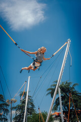 Girl jumping on bungee trampoline having fun in amusement park