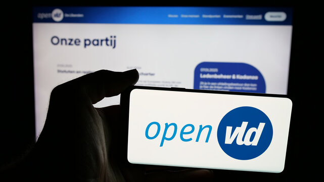 Stuttgart, Germany - 07-11-2025: Person holding mobile phone with logo of Open Vlaamse Liberalen en Democraten Open VLD on screen in front of web page. Focus on phone display.
