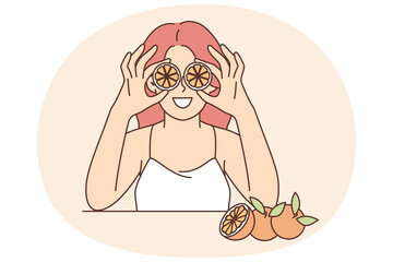 Woman holds slices of citrus fruit near eyes offering to use orange for rejuvenating facial mask