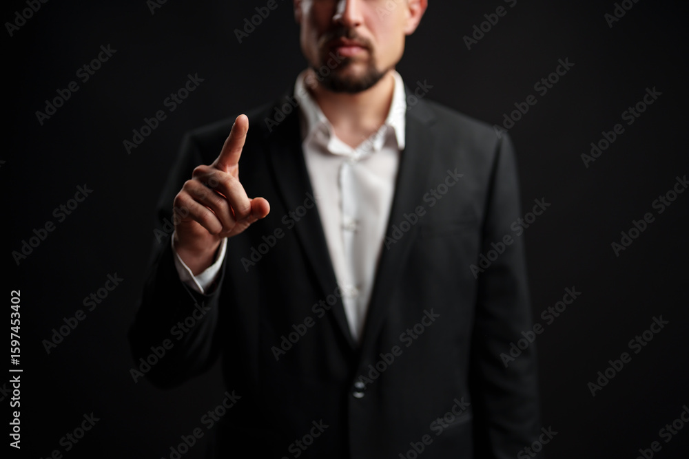 Poster businessman gestures with pointer finger in a serious demeanor against dark background during profes