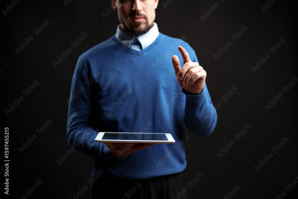 Poster professional man interacts with tablet in a dark studio setting during a digital presentation