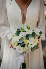 A bride in a long white wedding dress embroidered with various patterns with a deep neckline on her...