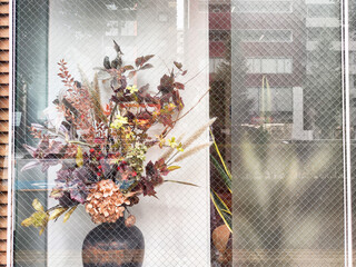 Bright, colorful flower arrangement displayed in a shop window on a busy city street during the...