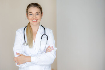 Confident female doctor smiling while standing with folded arms in medical uniform