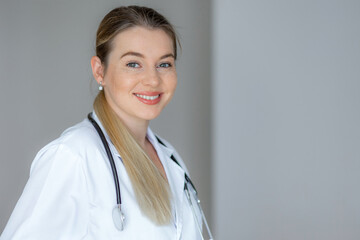 Smiling female doctor in white coat posing confidently with a stethoscope
