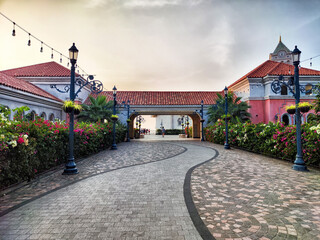 Scenic pathway through vibrant gardens leading to ocean view at sunset in a coastal town